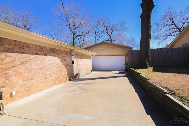 view of property exterior featuring an outbuilding, brick siding, fence, and a garage