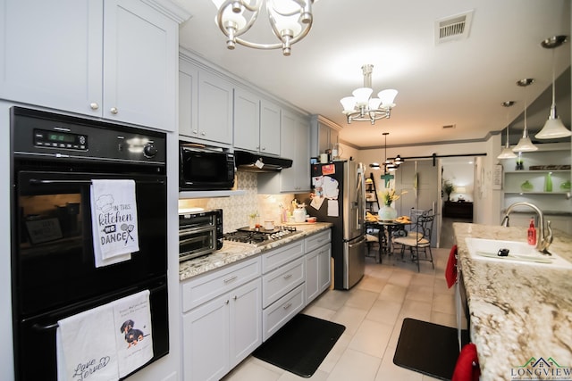 kitchen with visible vents, a barn door, an inviting chandelier, a sink, and black appliances