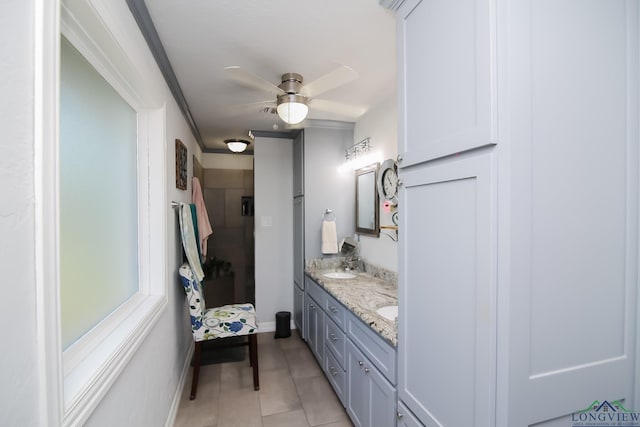 bathroom with ceiling fan, tile patterned flooring, a sink, baseboards, and double vanity