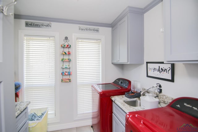 clothes washing area featuring ornamental molding, washer and clothes dryer, a sink, and cabinet space