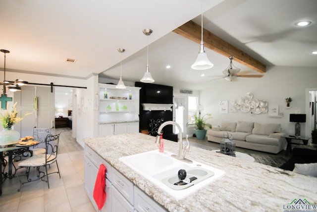 kitchen featuring visible vents, a barn door, a ceiling fan, a sink, and beamed ceiling