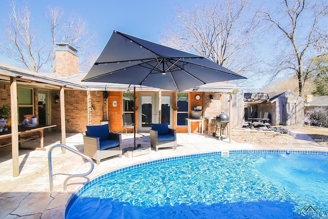 view of swimming pool with an outbuilding, a shed, a patio area, and a fenced in pool