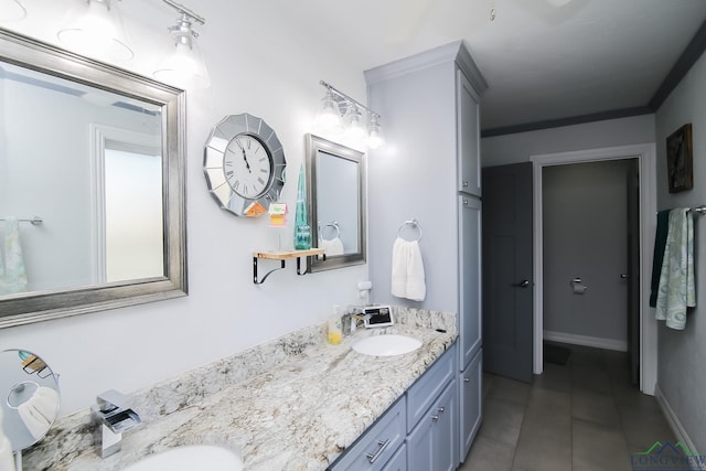 full bathroom featuring tile patterned floors, a sink, baseboards, and double vanity