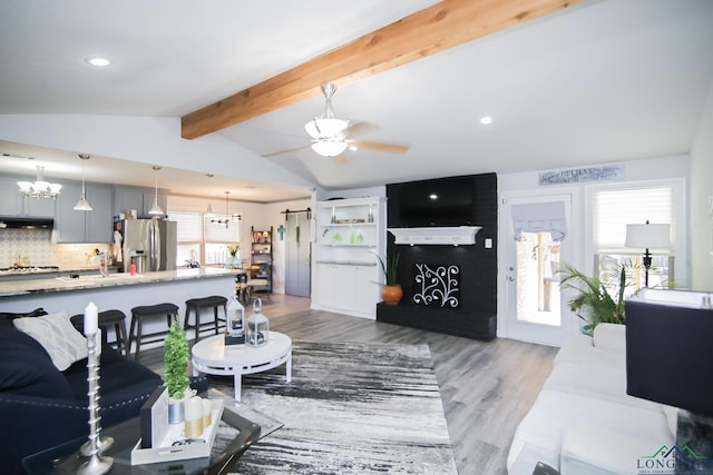 living area featuring vaulted ceiling with beams, recessed lighting, dark wood-type flooring, and ceiling fan with notable chandelier