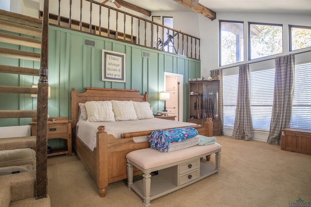 carpeted bedroom with a high ceiling and multiple windows