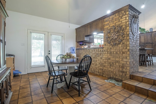 tiled dining space with brick wall, a wealth of natural light, and french doors