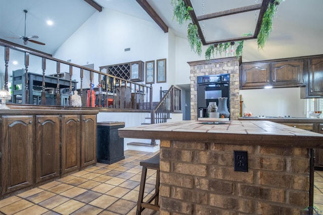 kitchen with dark brown cabinetry, a center island, and beamed ceiling