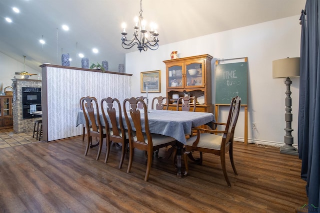 dining room with dark hardwood / wood-style flooring, a fireplace, lofted ceiling, and a notable chandelier