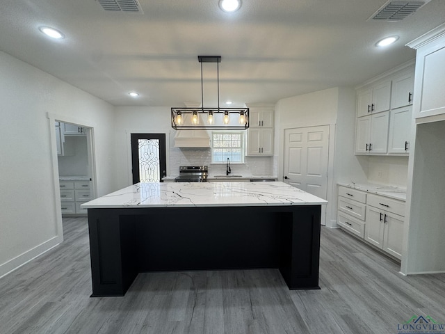 kitchen with white cabinetry, hanging light fixtures, stainless steel range with electric cooktop, and a kitchen island