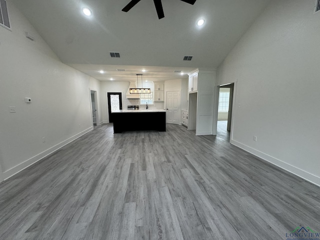 unfurnished living room with ceiling fan, lofted ceiling, hardwood / wood-style flooring, and sink