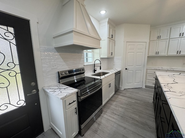 kitchen with custom exhaust hood, decorative backsplash, sink, white cabinetry, and stainless steel electric stove