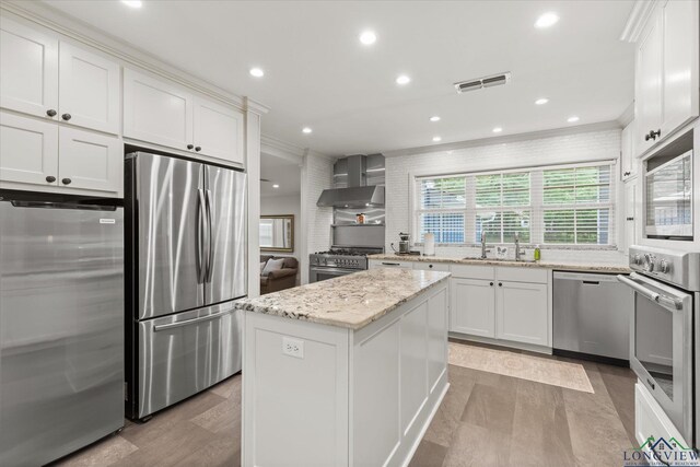 204 Delwood Dr, Longview, TX 75605 - kitchen featuring appliances with stainless steel finishes, wall chimney exhaust hood, ornamental molding, white cabinetry, and light stone counters
