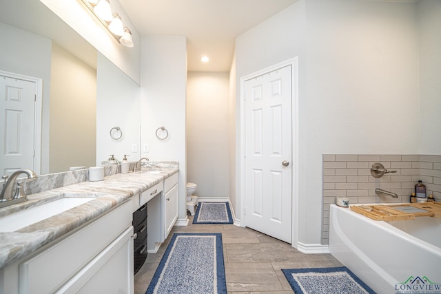 bathroom with a tub, vanity, and toilet