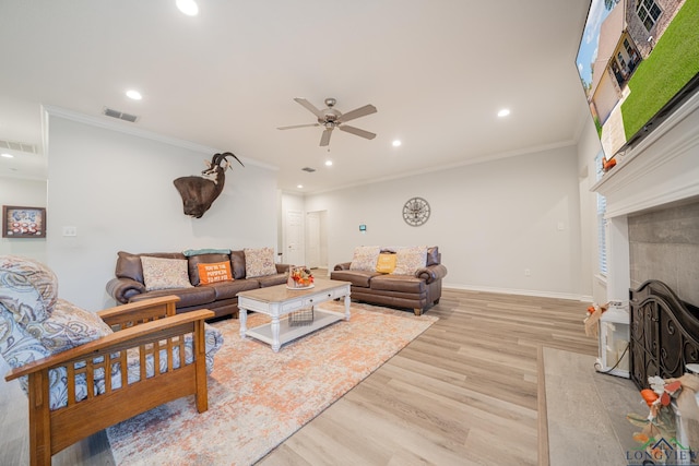 living room with a premium fireplace, ceiling fan, ornamental molding, and light hardwood / wood-style flooring