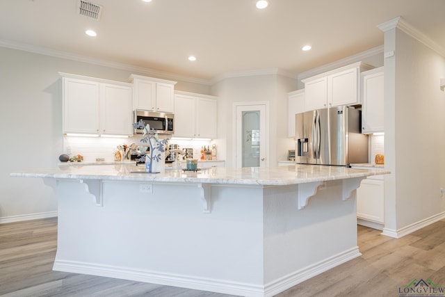 kitchen featuring a breakfast bar area, a large island with sink, white cabinets, and appliances with stainless steel finishes