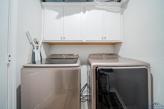 washroom featuring washing machine and clothes dryer and cabinets