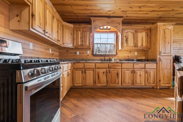 kitchen featuring wood finished floors, dark stone counters, stainless steel range with gas stovetop, wood walls, and wooden ceiling