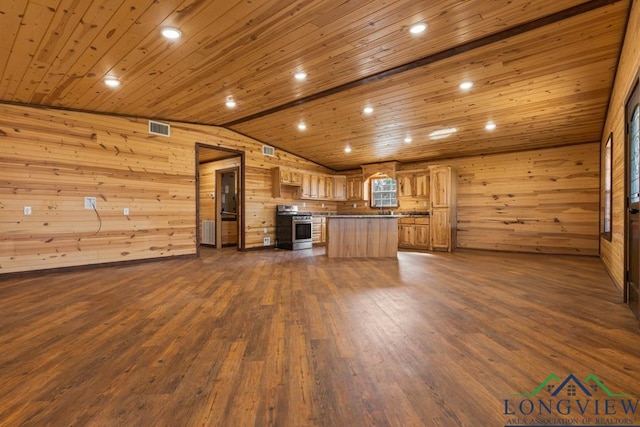 kitchen featuring wooden walls, dark wood-style floors, visible vents, and stainless steel gas range oven