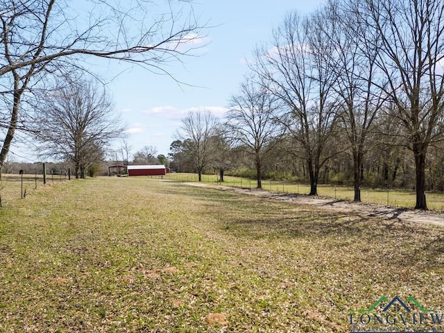 view of yard featuring an outbuilding, driveway, and a rural view