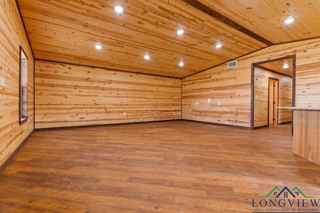 unfurnished room featuring visible vents, wooden walls, vaulted ceiling, wooden ceiling, and wood finished floors