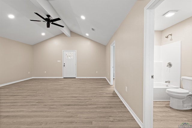 interior space featuring visible vents, a ceiling fan, light wood-style floors, baseboards, and vaulted ceiling with beams