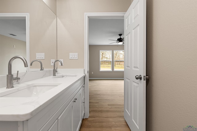 bathroom with a sink, a ceiling fan, wood finished floors, and double vanity