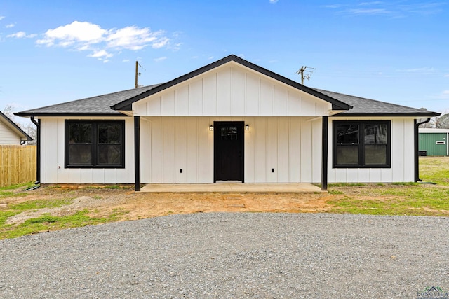 view of front of home featuring a patio, fence, and a shingled roof