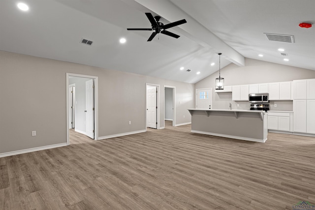 kitchen with open floor plan, stainless steel microwave, light wood finished floors, and visible vents