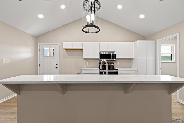 kitchen featuring a kitchen bar, lofted ceiling, light wood-type flooring, and stainless steel appliances