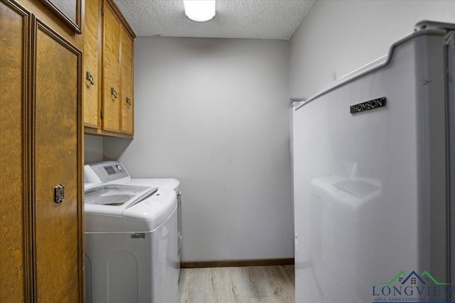 291 County Road 1130, Center, TX 75935 - laundry area with washing machine and clothes dryer, cabinet space, light wood-type flooring, and a textured ceiling