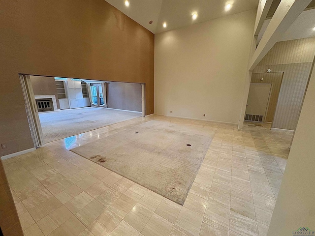 unfurnished living room with light tile patterned flooring and a towering ceiling