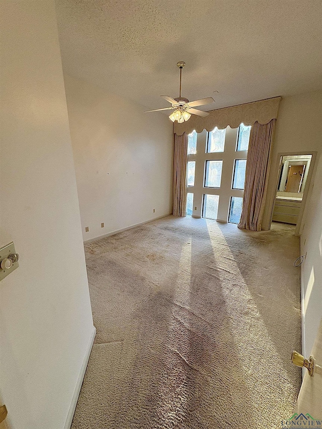 carpeted empty room featuring ceiling fan and a textured ceiling