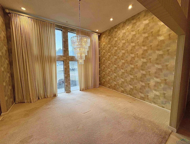 carpeted spare room featuring wooden walls and a notable chandelier