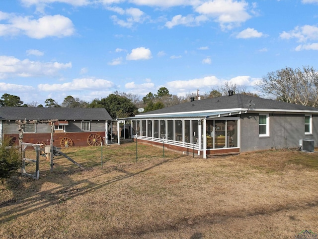 rear view of property featuring central AC, a lawn, and a sunroom