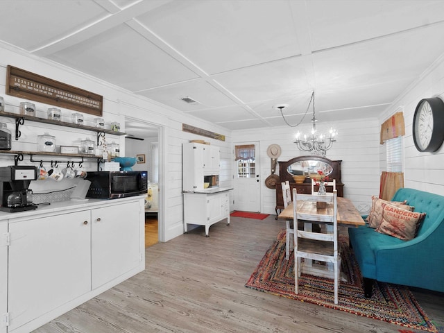 dining room featuring crown molding, coffered ceiling, a chandelier, and light wood-type flooring