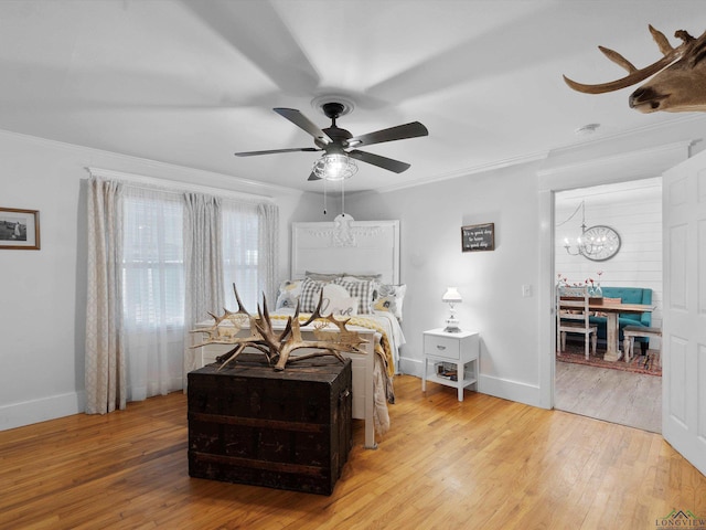 bedroom featuring crown molding, ceiling fan with notable chandelier, and light wood-type flooring