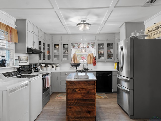 kitchen featuring hardwood / wood-style floors, stainless steel appliances, coffered ceiling, washer and dryer, and a kitchen island