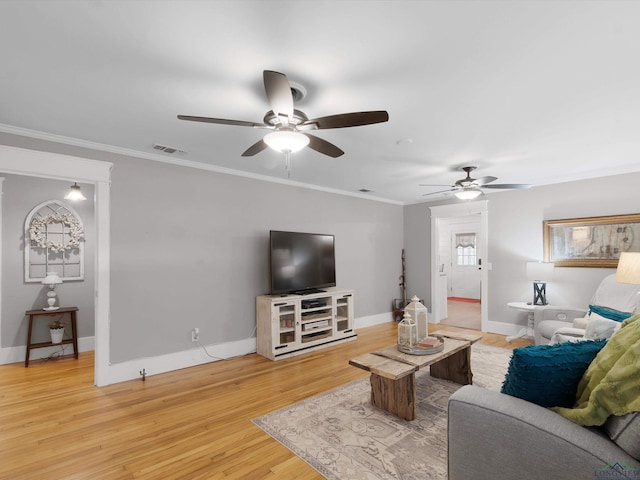 living room featuring wood-type flooring, ornamental molding, and ceiling fan