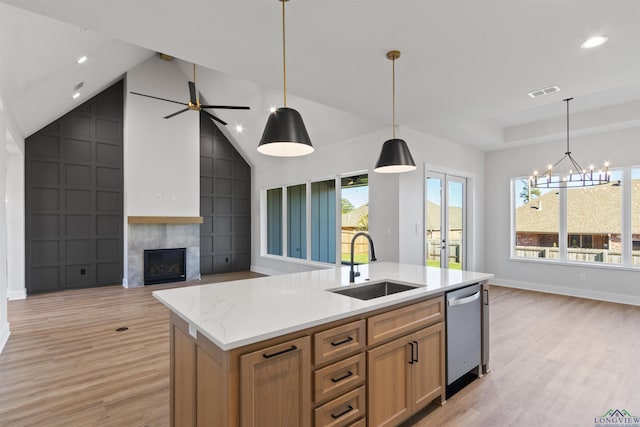 kitchen with dishwasher, sink, decorative light fixtures, and an island with sink