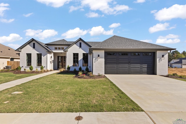 view of front of house with cooling unit, a garage, and a front yard