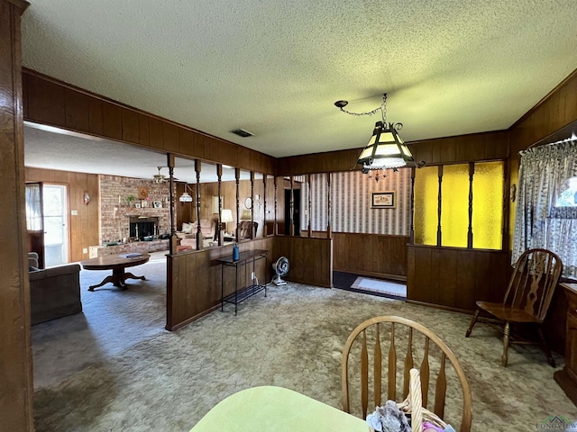 dining area with wooden walls, a fireplace, a textured ceiling, and carpet floors