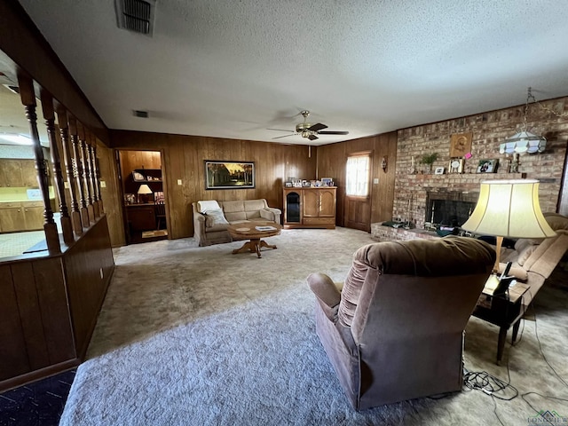 living room with a textured ceiling, wood walls, carpet, a fireplace, and ceiling fan