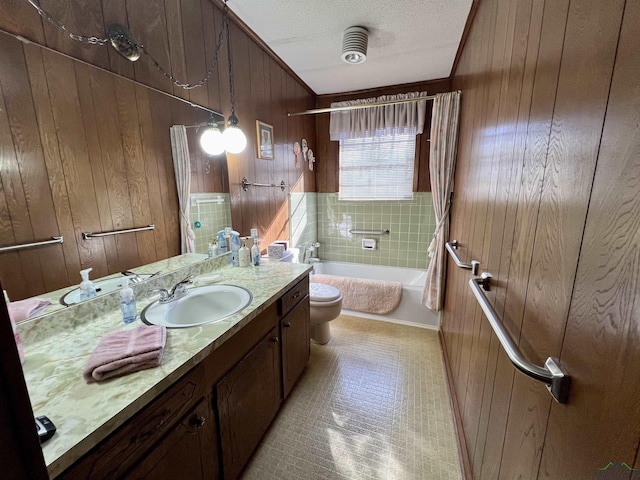 full bathroom featuring toilet, a textured ceiling, wooden walls, tiled shower / bath combo, and vanity