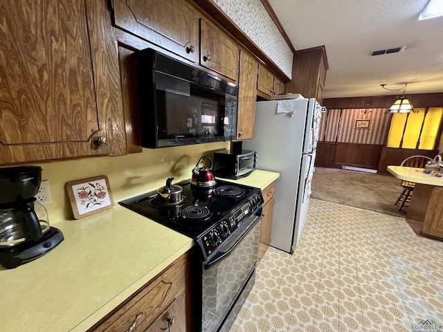 kitchen featuring wooden walls, a textured ceiling, and black appliances