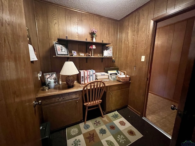 office space featuring built in desk, wood walls, and a textured ceiling