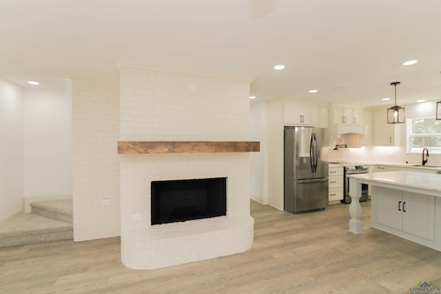 kitchen featuring appliances with stainless steel finishes, sink, pendant lighting, light hardwood / wood-style flooring, and white cabinets