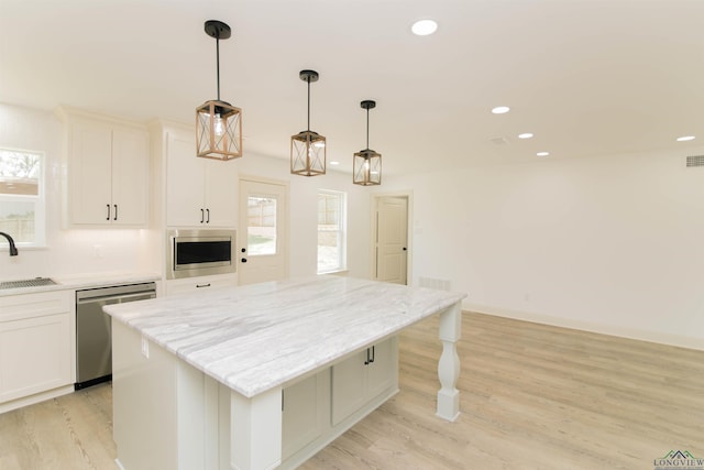 kitchen with pendant lighting, white cabinets, sink, a kitchen island, and stainless steel appliances