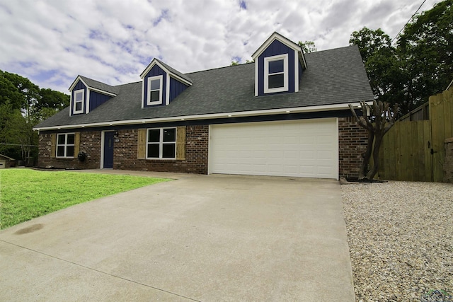 cape cod house featuring a garage and a front lawn