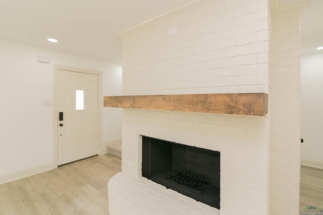 interior space with crown molding, wood-type flooring, and a brick fireplace