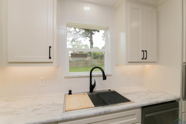 kitchen featuring dishwasher, white cabinets, light stone counters, and sink